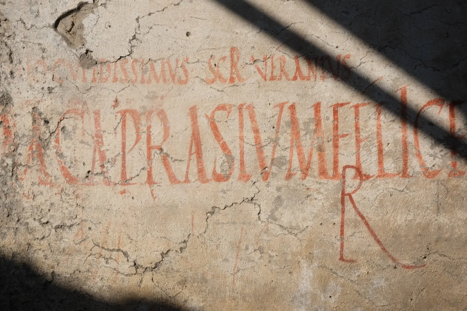 Weathered red lettering painted on plaster in Pompeii